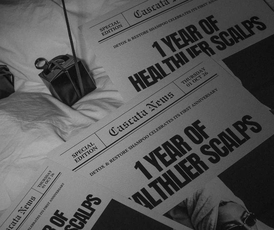 Black-and-white Cascata News birthday artwork celebrating one year of healthier scalps, beside a wrapped gift